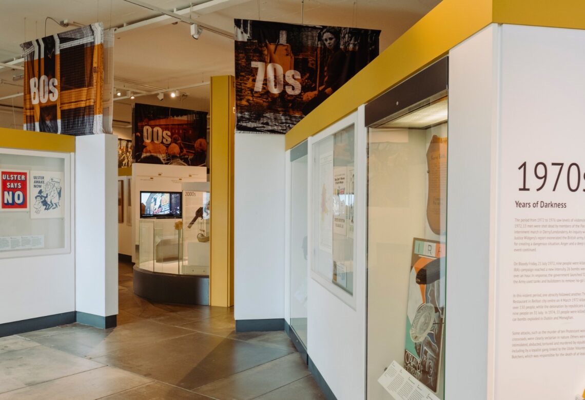The Troubles and Beyond exhibition at the Ulster Museum: display cases and banners marking the 1970s, 80s and 2000s.